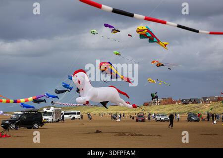 Cerfs-volants gonflables géants volant au-dessus de la plage lors d'un festival de cerf-volant à Lytham St Annes, avec des gens et des véhicules sur le sable. Banque D'Images