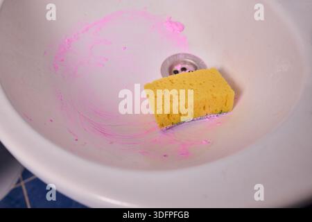 Propriétaire prépare la baignoire soigneusement, gros plan de l'écume de savon de nettoyage des mains du drain de la baignoire, vue détaillée de la personne désinfectant la baignoire avec de la mousse rose Banque D'Images