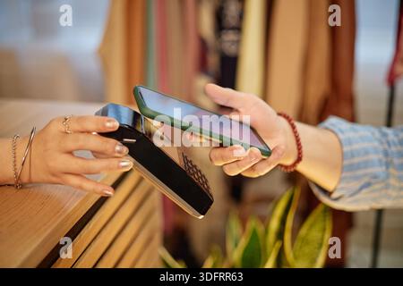 Caucasian jeune homme adulte payant pour l'achat de seconde main à l'aide d'un smartphone Banque D'Images
