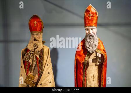 Paire de figurines antiques de Saint Nicolas vêtues de vêtements d'évêque traditionnels avec mitres rouges et détails faciaux sculptés. Banque D'Images