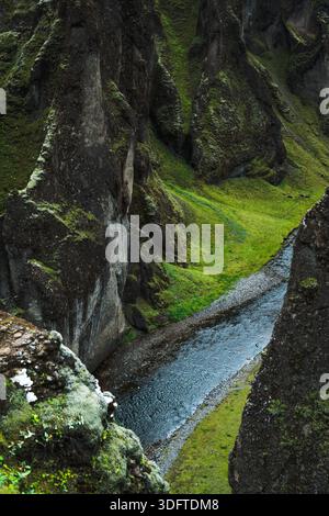 Vue d'une rivière serpentant à travers un canyon profond avec des falaises accidentées couvertes de mousse s'élevant de façon spectaculaire de chaque côté, Kirkjubaejarklaustur, Icel du Sud Banque D'Images
