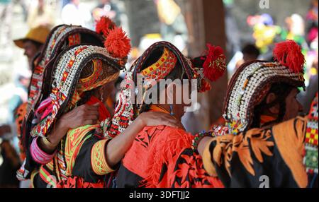 Kalash, Pakistan - 24 décembre 2025 : vue de femmes ornées de coiffes Kalash traditionnelles et de châles oranges vibrants, leurs subtilités de perles Banque D'Images