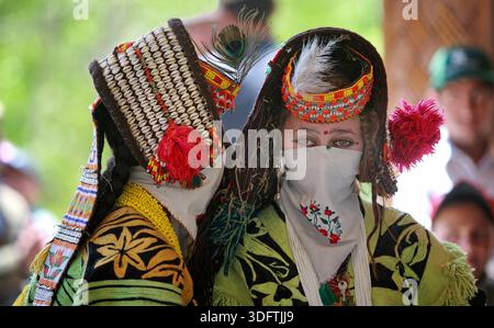 Kalash, Pakistan - 24 décembre 2025 : vue de deux femmes Kalash ornées de vêtements traditionnels vibrants, leurs visages partiellement voilés, debout contre A. Banque D'Images