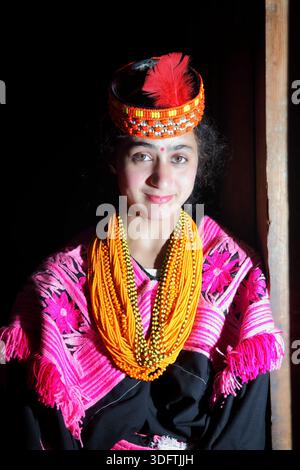 Kalash, Pakistan - 24 décembre 2025 : vue d'une fille Kalash, son sourire radieux contrastant avec le fond sombre, orné d'une tenue traditionnelle avec v Banque D'Images
