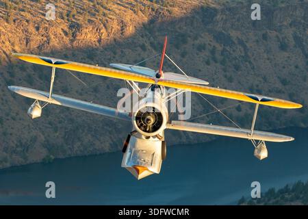 L'image montre un biplan amphibie Grumman J-2F-6 Duck en vol, vu en gros plan d'une perspective air-air avec le pilote visible dans le cockpit ouvert. Cet avion porte l'immatriculation civile N3960C et le numéro de construction 33559. Le J-2F-6 Duck a été construit par Grumman comme un biplan monomoteur à deux baies avec train d'atterrissage rétractable pour les opérations terrestres et maritimes. Il est propulsé par un moteur en étoile à neuf cylindres Wright R-1820 Cyclone refroidi par air. Cet oiseau de guerre restauré est exploité dans le cadre de la collection Erickson Airshow et représente une configuration Duck de production récente. Banque D'Images