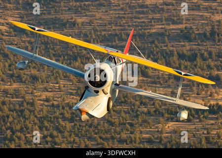 L'image montre un biplan amphibie Grumman J-2F-6 Duck en vol, vu en gros plan d'une perspective air-air avec le pilote visible dans le cockpit ouvert. Cet avion porte l'immatriculation civile N3960C et le numéro de construction 33559. Le J-2F-6 Duck a été construit par Grumman comme un biplan monomoteur à deux baies avec train d'atterrissage rétractable pour les opérations terrestres et maritimes. Il est propulsé par un moteur en étoile à neuf cylindres Wright R-1820 Cyclone refroidi par air. Cet oiseau de guerre restauré est exploité dans le cadre de la collection Erickson Airshow et représente une configuration Duck de production récente. Banque D'Images