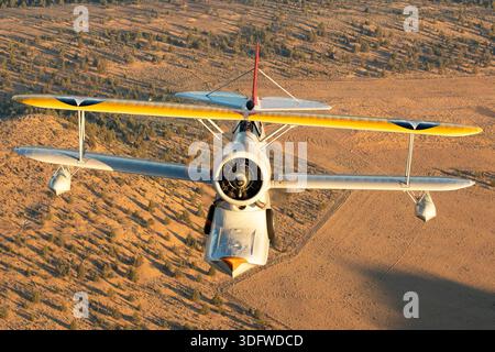 L'image montre un biplan amphibie Grumman J-2F-6 Duck en vol, vu en gros plan d'une perspective air-air avec le pilote visible dans le cockpit ouvert. Cet avion porte l'immatriculation civile N3960C et le numéro de construction 33559. Le J-2F-6 Duck a été construit par Grumman comme un biplan monomoteur à deux baies avec train d'atterrissage rétractable pour les opérations terrestres et maritimes. Il est propulsé par un moteur en étoile à neuf cylindres Wright R-1820 Cyclone refroidi par air. Cet oiseau de guerre restauré est exploité dans le cadre de la collection Erickson Airshow et représente une configuration Duck de production récente. Banque D'Images