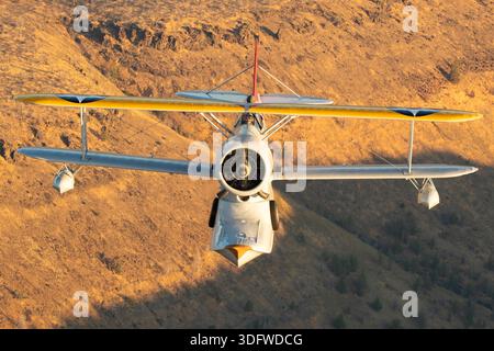 L'image montre un biplan amphibie Grumman J-2F-6 Duck en vol, vu en gros plan d'une perspective air-air avec le pilote visible dans le cockpit ouvert. Cet avion porte l'immatriculation civile N3960C et le numéro de construction 33559. Le J-2F-6 Duck a été construit par Grumman comme un biplan monomoteur à deux baies avec train d'atterrissage rétractable pour les opérations terrestres et maritimes. Il est propulsé par un moteur en étoile à neuf cylindres Wright R-1820 Cyclone refroidi par air. Cet oiseau de guerre restauré est exploité dans le cadre de la collection Erickson Airshow et représente une configuration Duck de production récente. Banque D'Images