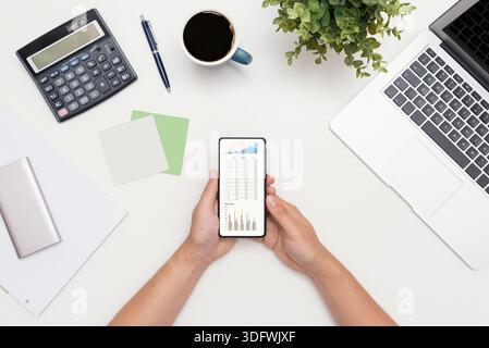 Analyst travaille avec les données. Graphiques sur l'écran du smartphone, composition de la pose à plat Banque D'Images