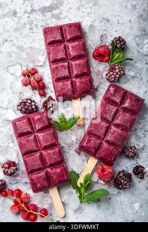 baies crème glacée popsicles avec des baies congelées sur fond gris, vue de dessus Banque D'Images