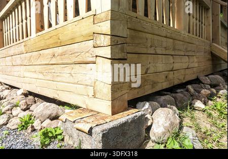Coin de la maison en bois sur la base de pierre de support Banque D'Images