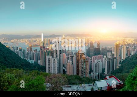 Vue aérienne du port de Hong Kong avec sa ligne d'horizon animée, ses gratte-ciel emblématiques au coucher du soleil, son ciel clair, son énergie urbaine, son architecture moderne Banque D'Images