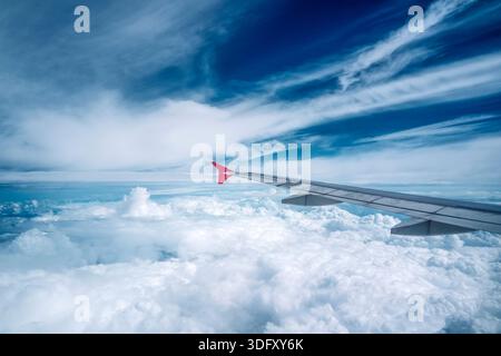 Nuages moelleux vus à travers la fenêtre d'un avion. Vue depuis la fenêtre de l'avion sur un beau ciel nuageux et l'aile de l'avion. Banque D'Images