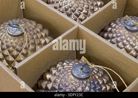 Décorations d'arbre de Noël, boules dorées en forme de pommes de pin, dans une boîte en carton, gros plan, fond abstrait Banque D'Images