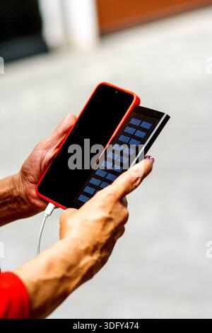 Mains tenant smartphone charge avec panneau solaire portable Banque D'Images