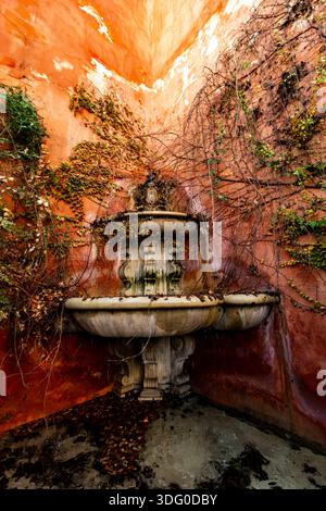 Une charmante fontaine à deux niveaux avec un lierre luxuriant décore un coin vibrant d'un bâtiment à Séville, reflétant la beauté rustique espagnole. Banque D'Images