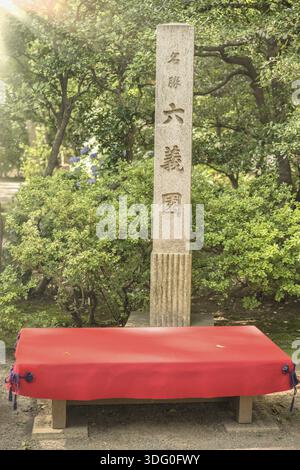 Pierre rectangulaire qui témoignent du statut de national japonais site pittoresque dans le jardin Rikugien à Tokyo. Bancs en bois recouverte de feutre rouge sont ava Banque D'Images