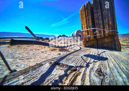 Poteau de clôture de fil barbelé et isolant en céramique dans le paysage du désert de Californie Banque D'Images