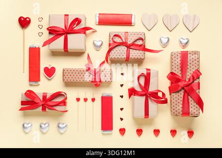 Boîtes cadeaux avec bonbons et coeurs décoratifs sur fond beige. Célébration de la Saint-Valentin Banque D'Images