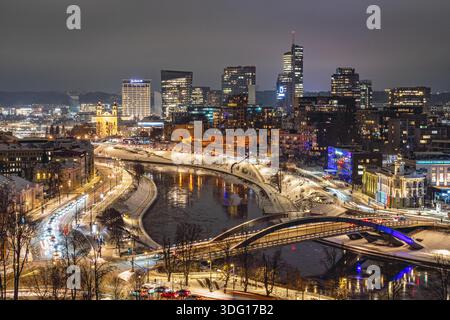 Une vue nocturne hivernale de Vilnius montrant un paysage urbain lumineux le long de la rivière Neris, avec des ponts illuminés, un trafic fluide Banque D'Images