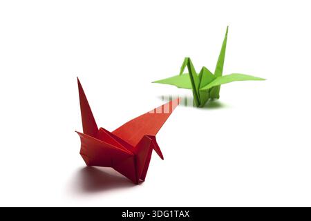 Grue en papier origami rouge et vert sur papier blanc Banque D'Images