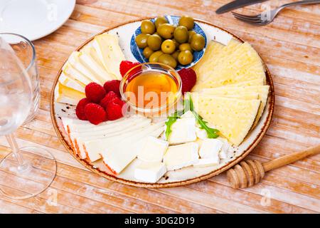 Différents types de fromage, miel, framboises et olives sur bois Banque D'Images