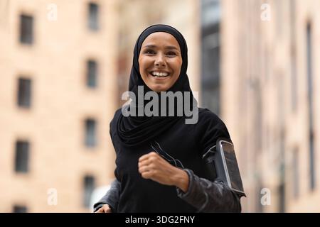 Portrait de la jeune fille islamique heureuse en hijab jogging en plein air Banque D'Images