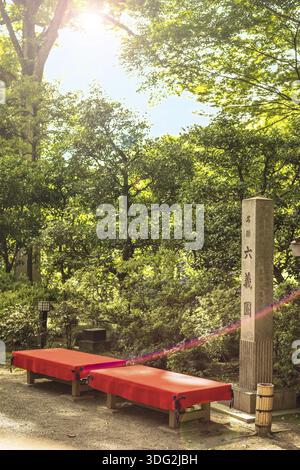 Pierre rectangulaire qui témoignent du statut de national japonais site pittoresque dans le jardin Rikugien à Tokyo. Bancs en bois recouverte de feutre rouge sont ava Banque D'Images