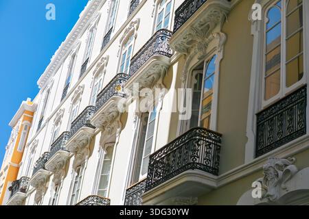 Vue sur la façade d'un bâtiment historique de plusieurs étages orné de sculptures en stuc ornées et de balcons en fer forgé. Mélange de style architectural de néoclassique Banque D'Images