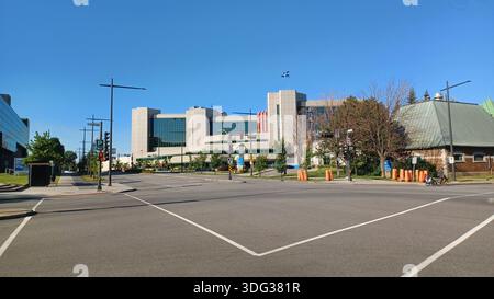 Montréal, QC, Canada - 7 août 2025 : paysage urbain de Québec avec un bâtiment moderne arborant le drapeau du Québec, des feux de circulation et des panneaux de signalisation Banque D'Images
