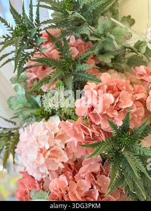 Gros plan élégant de fleurs d'hortensia roses avec un feuillage vert luxuriant, stylisé comme un arrangement floral décoratif dans une lumière naturelle douce. Banque D'Images
