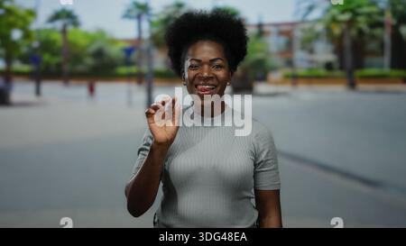 Femme souriante langue dans la rue urbaine saluant à l'extérieur sous le ciel ensoleillé expression joyeuse captivante et geste amical capturant vivant Banque D'Images