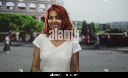 Femme souriant et applaudissant les mains devant le bâtiment du colisée dans une rue bondée ; souvenir de voyage de joie. Banque D'Images