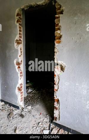 Une ouverture brutale, créée par la force dans le mur d'un bâtiment en décomposition laisse entendre à l'intrusion, la destruction et l'abandon. Banque D'Images