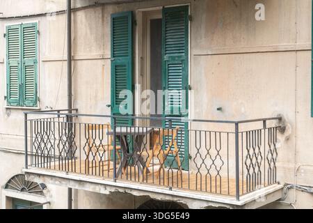 Balcon italien traditionnel avec volets verts et chaises en bois. Architecture résidentielle européenne et concept de style de vie méditerranéen Banque D'Images