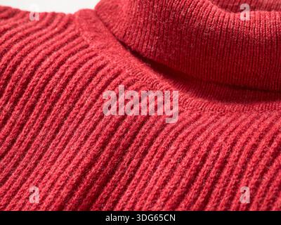 Gros plan du pull à col roulé côtelé rouge montrant la texture et les coutures. Banque D'Images