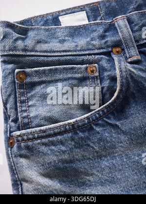 Gros plan de Jean denim bleu avec coutures visibles et rivets en laiton. Banque D'Images