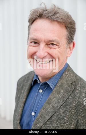 Souriant homme plus âgé dans une veste texturée et chemise en denim sur un fond clair Italie Banque D'Images