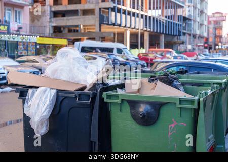 Poubelles débordantes devant un bâtiment urbain avec balcons et enseignes de magasin Banque D'Images