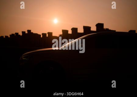 Silhouette d'une voiture et d'un horizon urbain sur fond de coucher de soleil chaud. Shanghai, Chine Banque D'Images