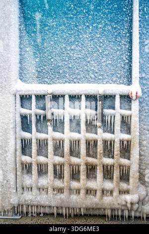 Dommages causés par les intempéries hivernales : le support métallique pour nettoyer et sécher les tapis de voiture entièrement recouvert d'une accumulation de glace importante Banque D'Images