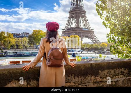 Une femme touriste se tient au bord de la Seine et profite de la belle vue sur la Tour Eiffel à Paris, France Banque D'Images