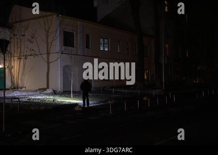 Kiev, Ukraine – 21 décembre 2022 : Ivana Franka Street Man marche avec Jack Russell Terrier chien en utilisant une lampe de poche pendant la panne. Lumière sur le trottoir. Énergie Banque D'Images