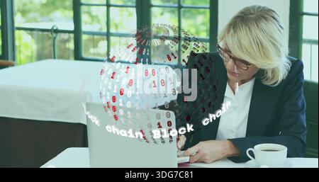 Écrivant femme dans le blazer sombre au café, travaillant sur ordinateur portable à côté de l'ordinateur portable avec bloc chaîne globe Banque D'Images