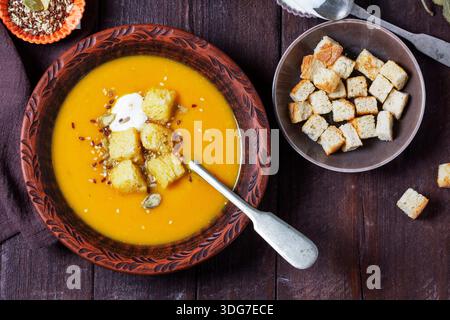 Soupe à la crème de citrouille servie avec des croûtons, de la crème et des graines. Banque D'Images