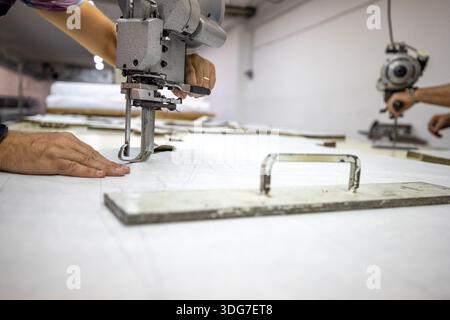 Tailleur utilisant une coupeuse électrique verticale pour textile militaire. Fabrication industrielle d'uniformes militaires tactiques suivant des schémas précis en professionno Banque D'Images