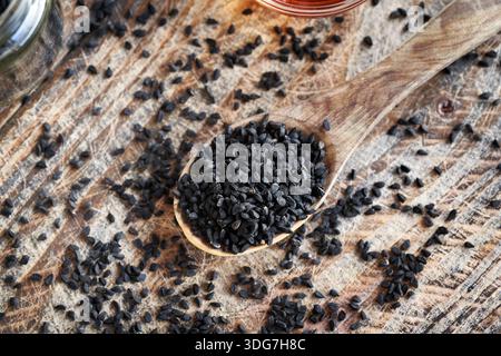 Cumin noir ou graines de Nigella sativa sur une cuillère en bois, vue de dessus Banque D'Images