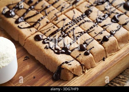Barres de collation sans gluten faites maison à base de poudre de protéines de lactosérum, farine d'amande, sirop d'érable, vanille et beurre d'arachide, enrobées de chocolat Banque D'Images