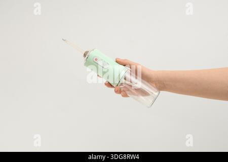 Main féminine tenant l'irrigateur oral sur fond blanc Banque D'Images