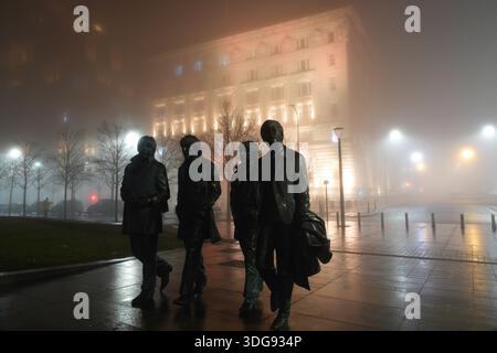 Liverpool, Royaume-Uni. 16 janvier 2026. Météo britannique. Une épaisse couverture de brouillard a commencé à s'installer sur Merseyside ce soir. Un avertissement météorologique jaune a été mis en place avec du brouillard qui devrait affecter l'ensemble du Merseyside. Cette image d'ambiance montre la statue des Beatles avec le Royal Liver Building et le Cunard Building entourés d'une couverture dense de brouillard nocturne. Crédit : Liverpool Live News/Alamy Live News Banque D'Images